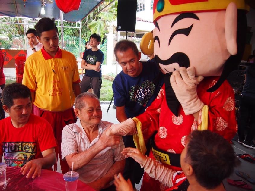 Old folks were eagerly waiting to shake hands with the God of Prosperity mascot.